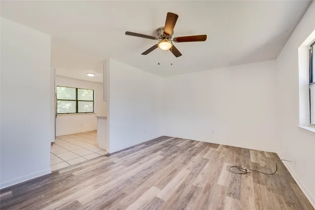a view of empty room with wooden floor and ceiling fan