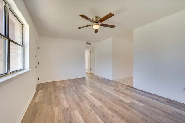 a view of empty room with wooden floor and fan