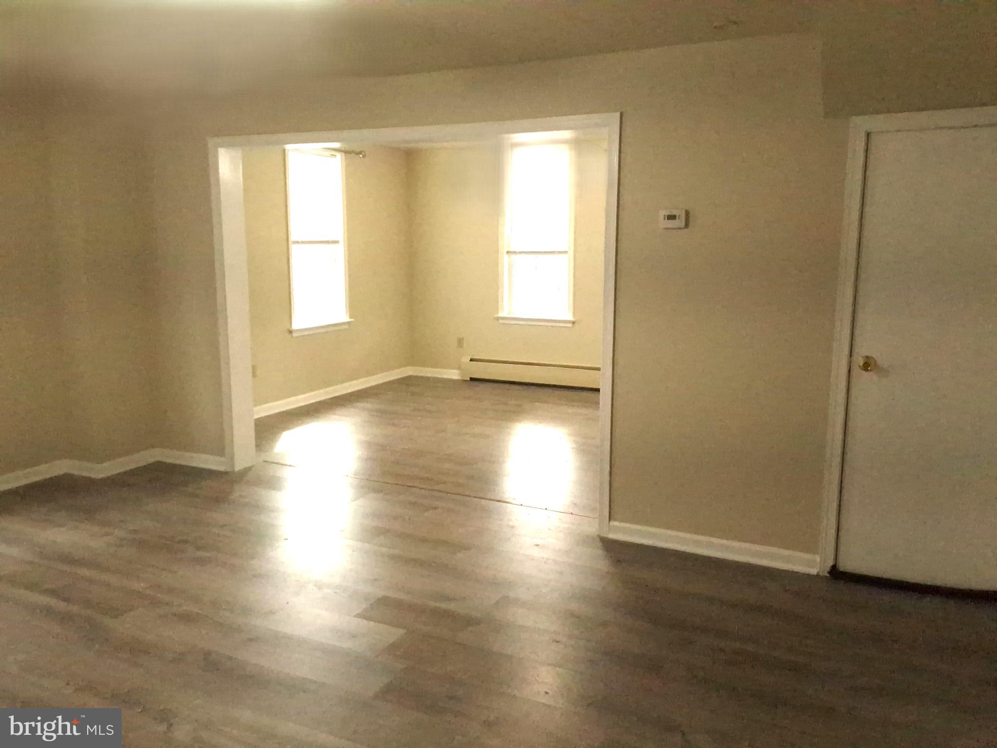59 West Slokom Avenue Christiana, PA 17509 - Photo 5 of 28 an empty room with wooden floor and windows with curtains