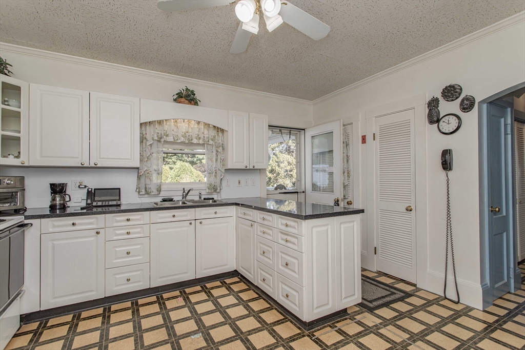 643 Center Street Raynham, MA 02767 - Photo 8 of 42 a kitchen with granite countertop white cabinets and white appliances