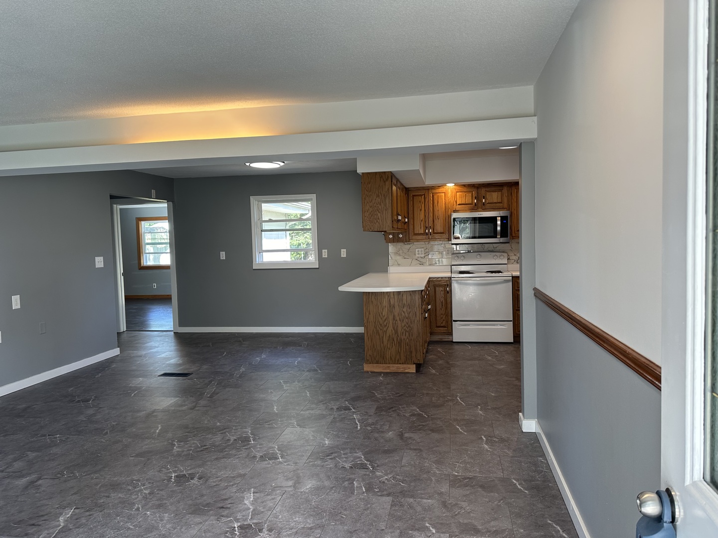203 Ruby Street Villa Grove, IL 61956 - Photo 3 of 18 a view of a kitchen with a sink wooden cabinets and a living room