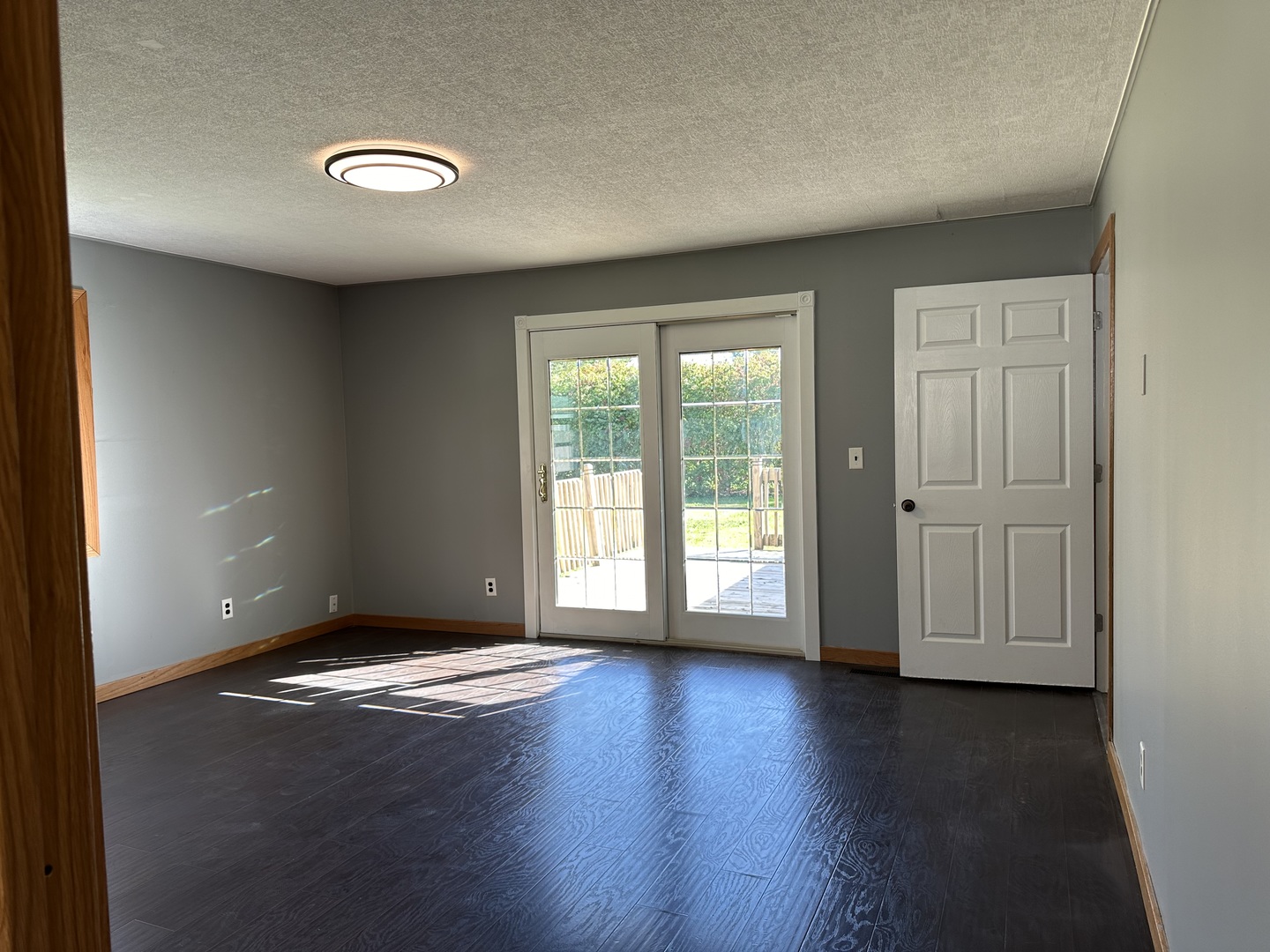 203 Ruby Street Villa Grove, IL 61956 - Photo 6 of 18 an empty room with wooden floor and windows