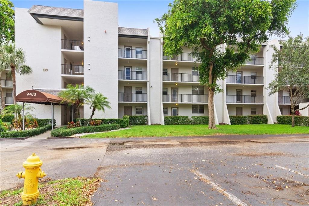 9470 Poinciana Place, Unit 103 Davie, FL 33324 - Photo 6 of 27 a tall yellow building sitting in front of a building