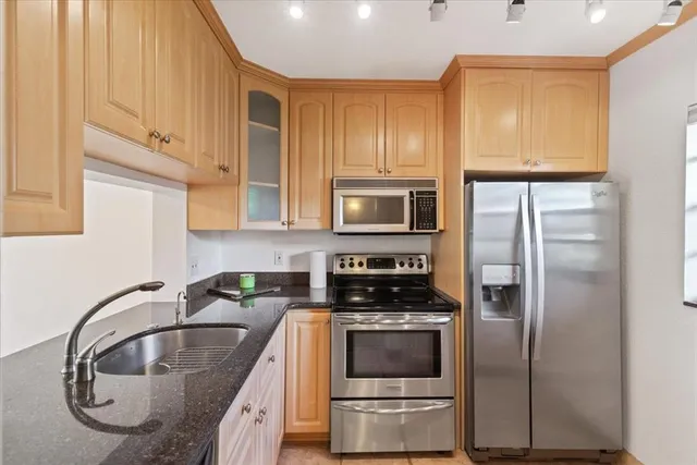 a kitchen with stainless steel appliances granite countertop a refrigerator a stove and a sink with wooden floor