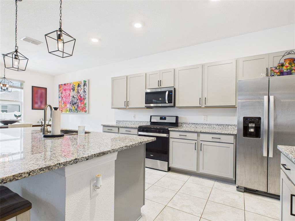 6506 Southwest 75th Ave Road Ocala, FL 34474 - Photo 15 of 28 a kitchen with stainless steel appliances granite countertop a sink a stove top oven a chimney cabinets and a counter top space