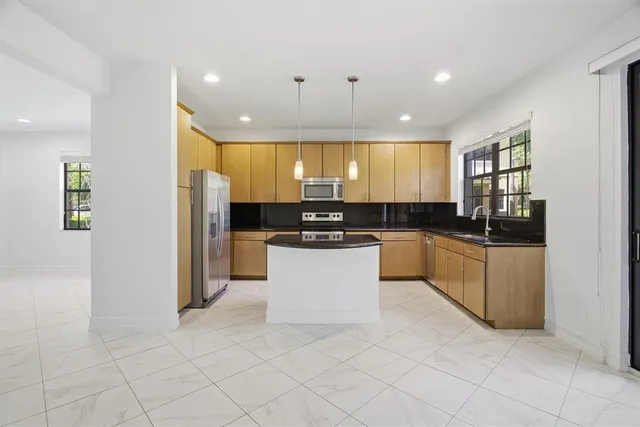 a kitchen with granite countertop a refrigerator and cabinets