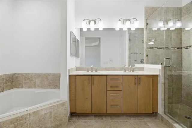 a bathroom with a double vanity sink a mirror a shower and bathtub