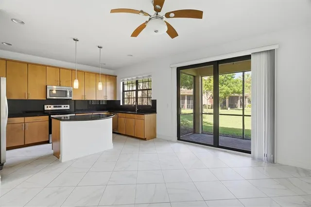 a large kitchen with kitchen island granite countertop a stove a sink a counter space and stainless steel appliances
