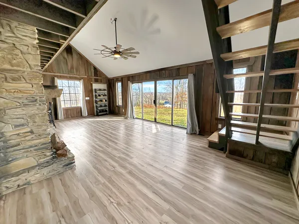 an empty room with wooden floor chandelier and windows