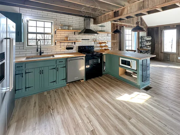 a kitchen with stainless steel appliances granite countertop a refrigerator a sink dishwasher a stove and white countertops with wooden floor