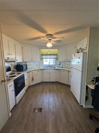 a kitchen with a hard wood floor a sink a window and stainless steel appliances