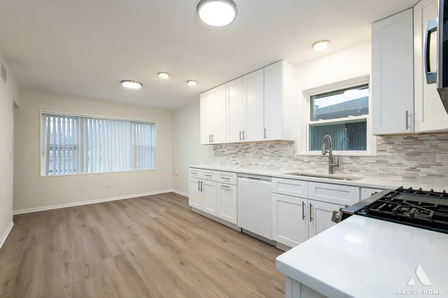 a kitchen with a sink a stove a refrigerator and white cabinets