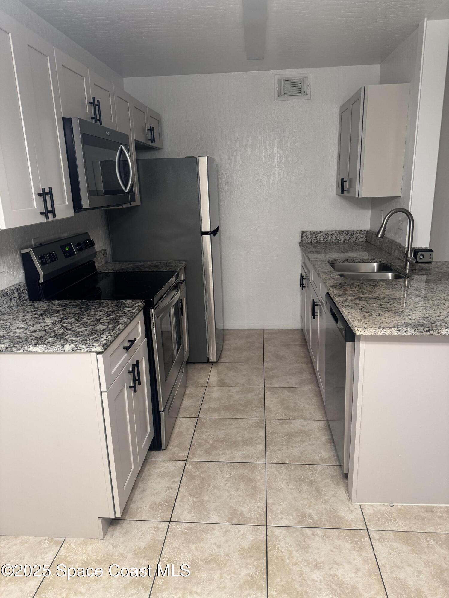 3212 Tree Ridge Lane Northeast Palm Bay, FL 32905 - Photo 3 of 8 a kitchen with a stove top oven and sink