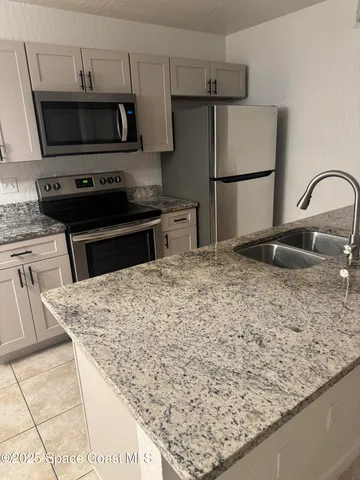 a kitchen with granite countertop a refrigerator and a sink