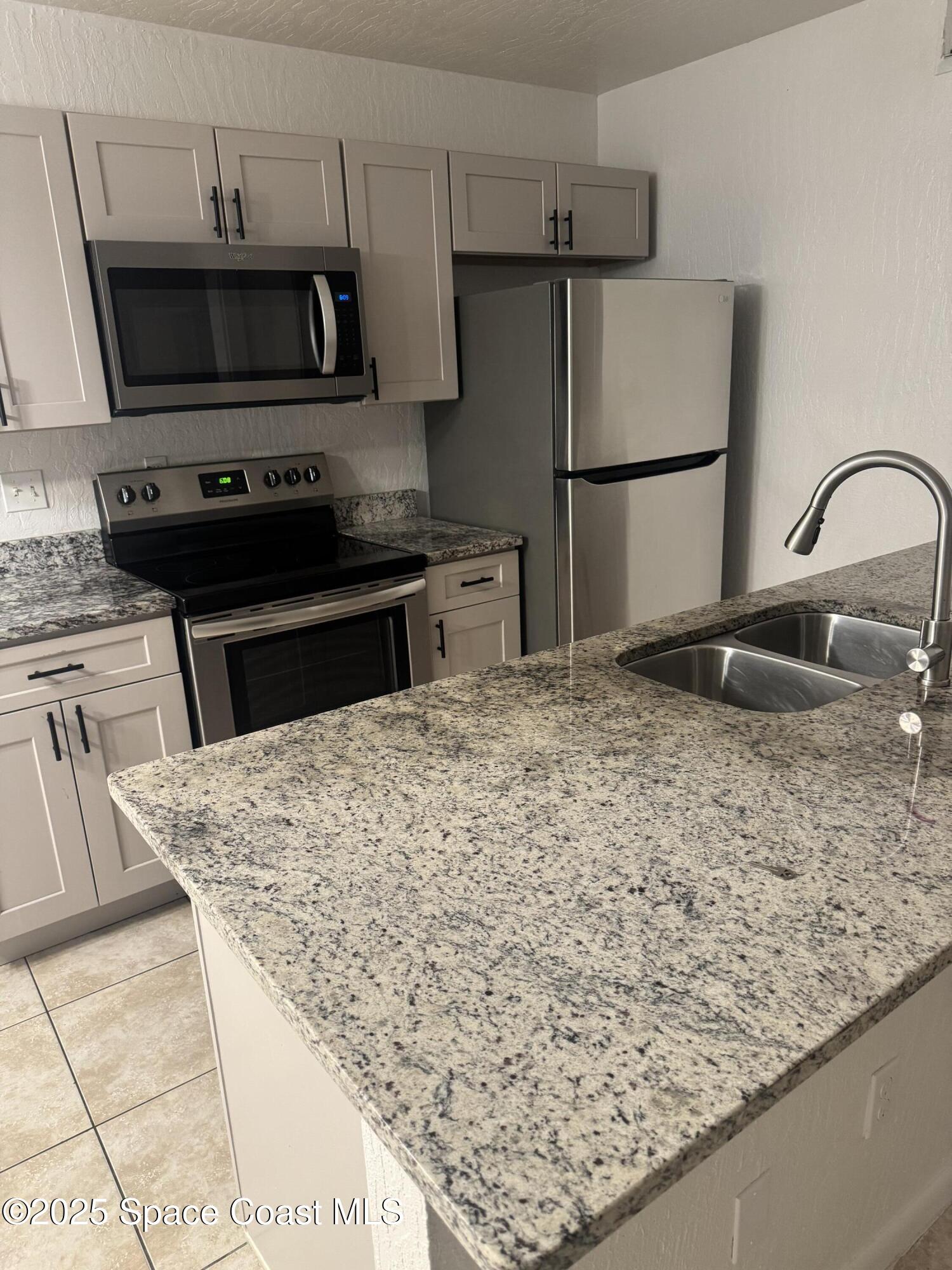 3212 Tree Ridge Lane Northeast Palm Bay, FL 32905 - Photo 4 of 8 a kitchen with granite countertop a refrigerator and a sink