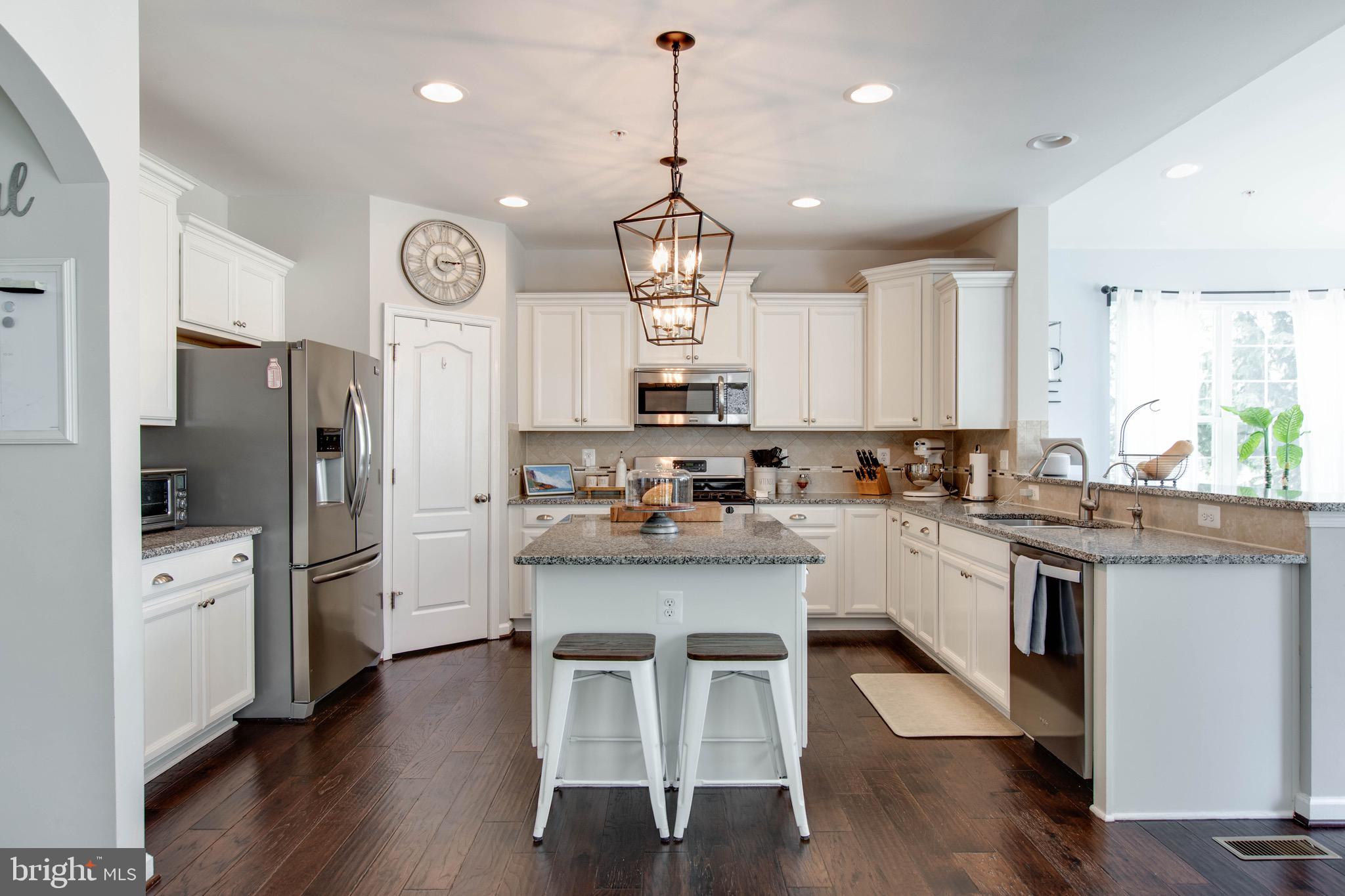 7870 Sunhaven Way Severn, MD 21144 - Photo 20 of 70 a kitchen with stainless steel appliances granite countertop a stove a sink dishwasher a refrigerator and a dining table with wooden floor