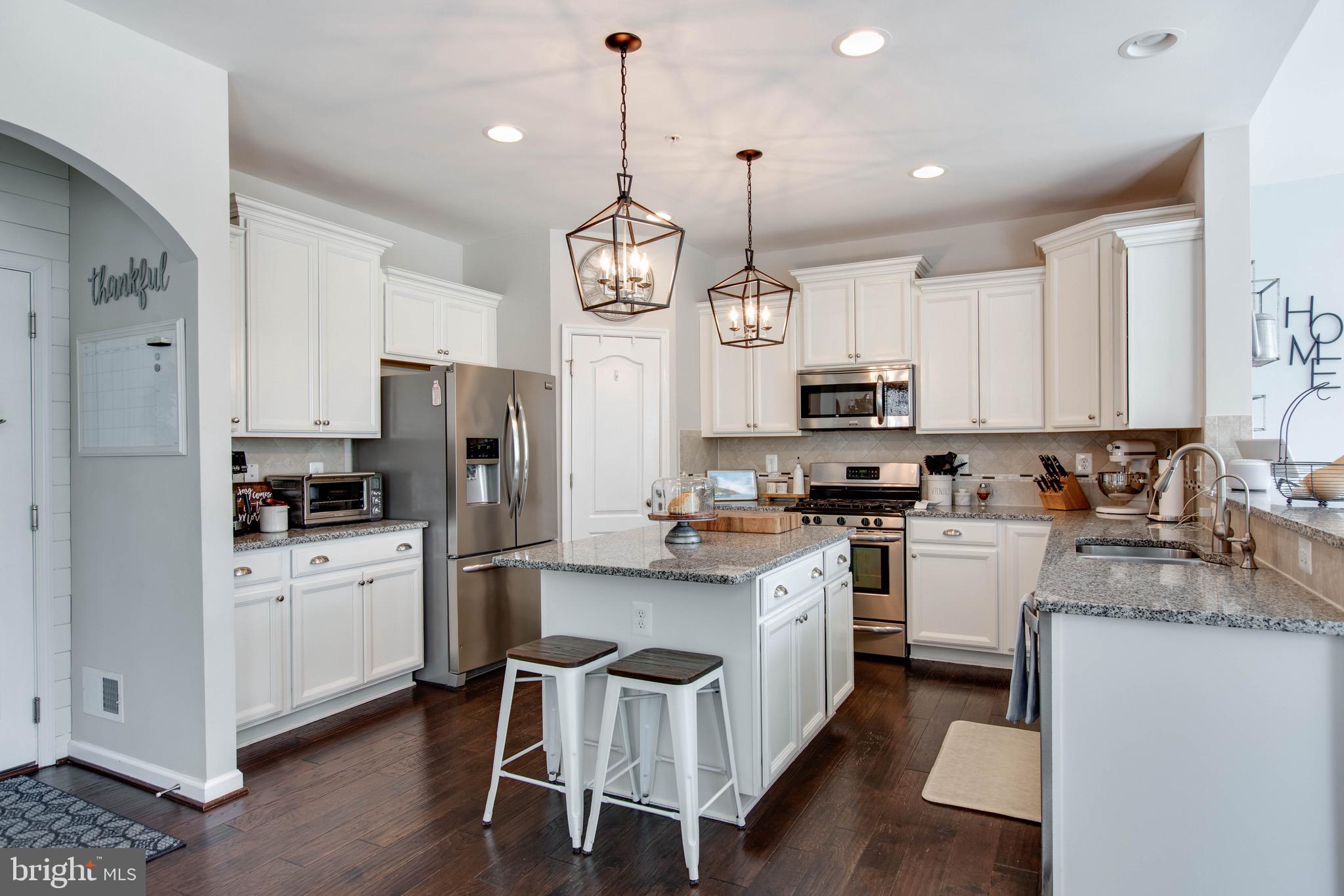 7870 Sunhaven Way Severn, MD 21144 - Photo 21 of 70 a kitchen with stainless steel appliances granite countertop a refrigerator a sink dishwasher a stove and white cabinets with wooden floor