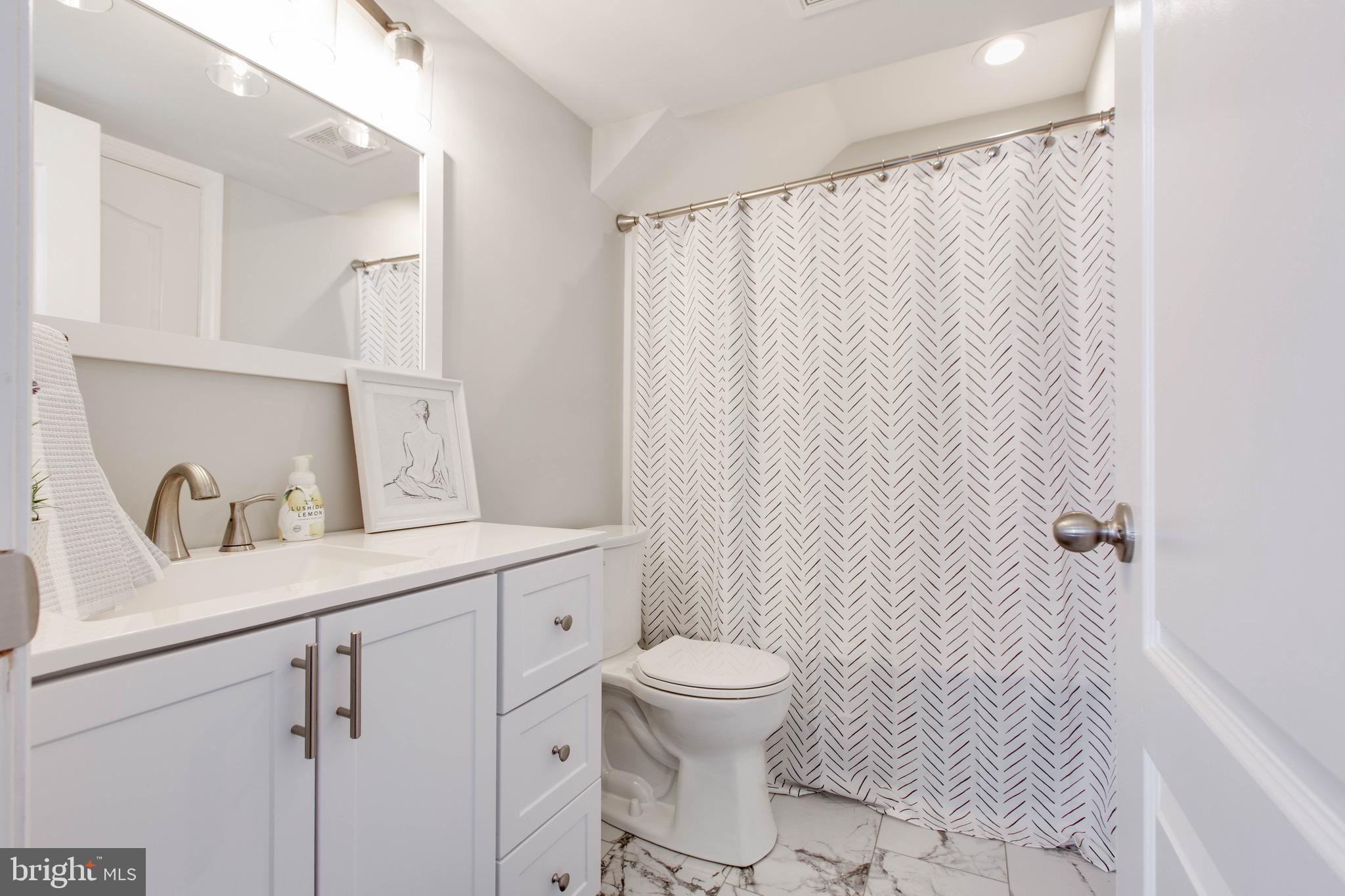 7870 Sunhaven Way Severn, MD 21144 - Photo 52 of 70 a bathroom with a sink a toilet and shower curtain