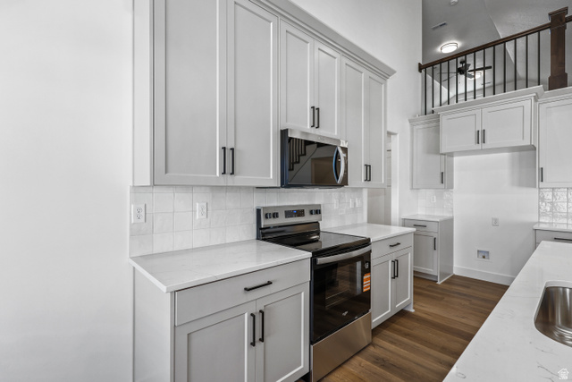 1139 South 4475 West West Point, UT 84015 - Photo 11 of 33 Kitchen with stainless steel appliances, tasteful backsplash, dark wood-type flooring, light stone counters, and white cabinets