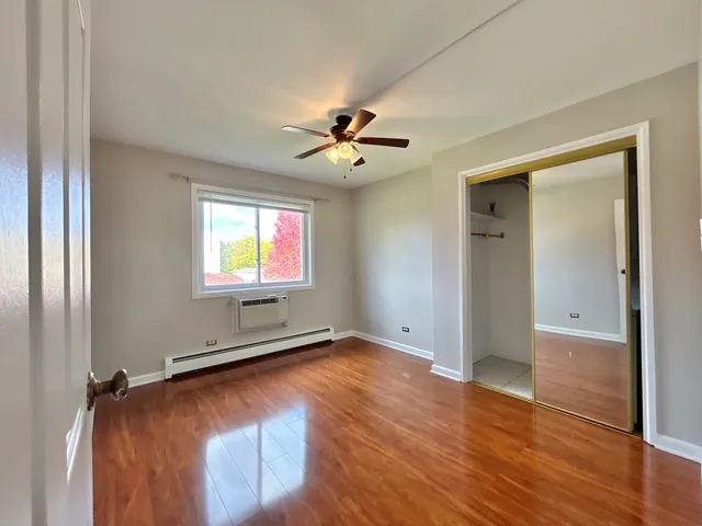 an empty room with wooden floor and a ceiling fan