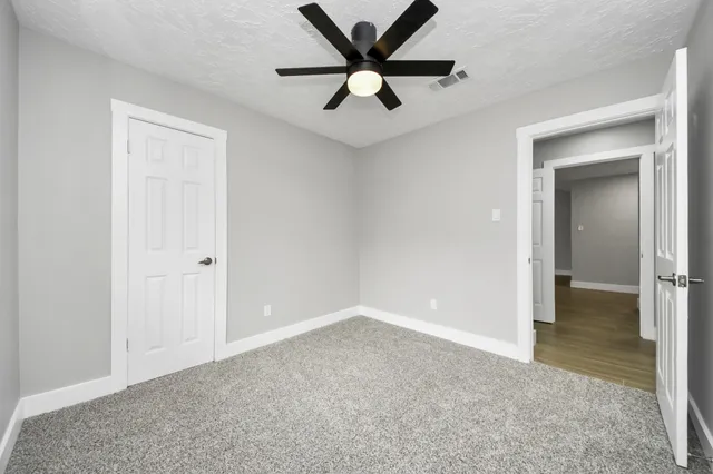 an empty room with windows and fan