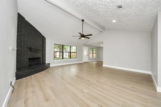 an empty room with windows and fireplace
