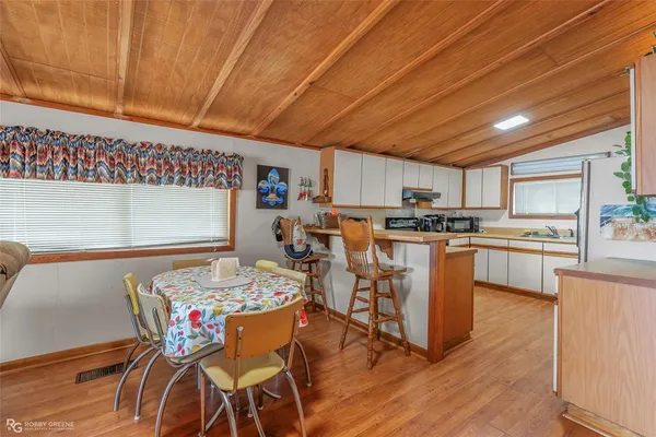a kitchen with stainless steel appliances kitchen island granite countertop a table chairs and a wooden floor