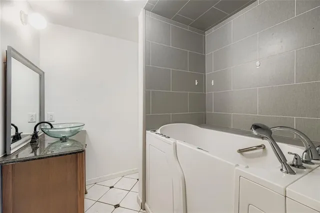 a bathroom with a granite countertop sink and a washing machine