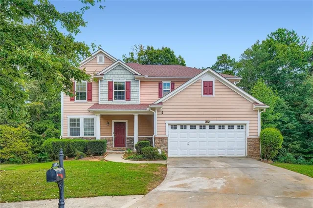 a view of a white house with a small yard and large trees