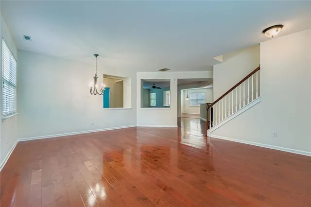 a view of an empty room with wooden floor and staircase