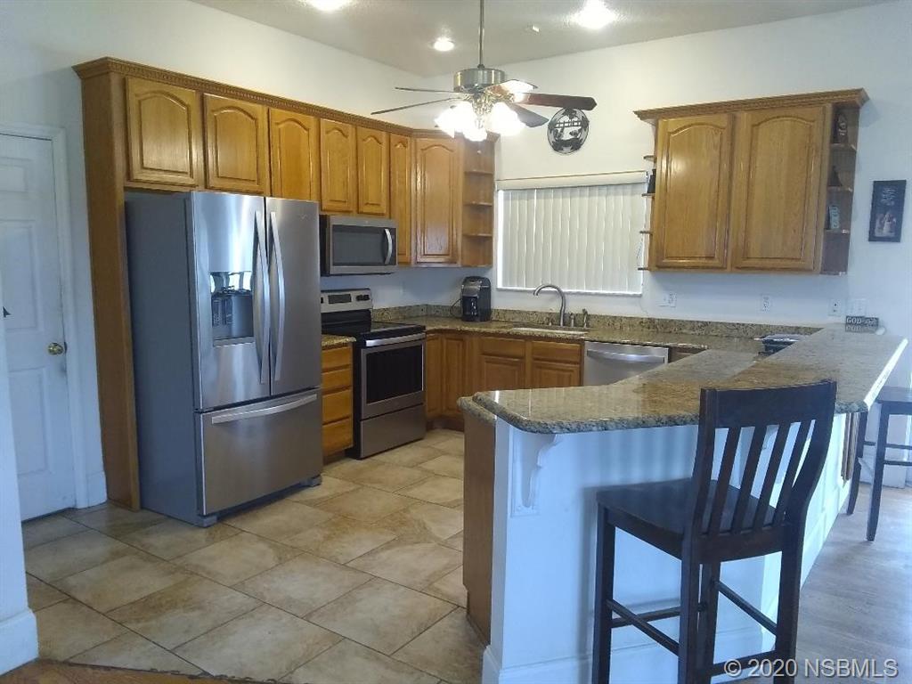 415 Stacy Grove Road Oak Hill, FL 32759 - Photo 12 of 25 a kitchen with a refrigerator a sink dishwasher a stove and a refrigerator