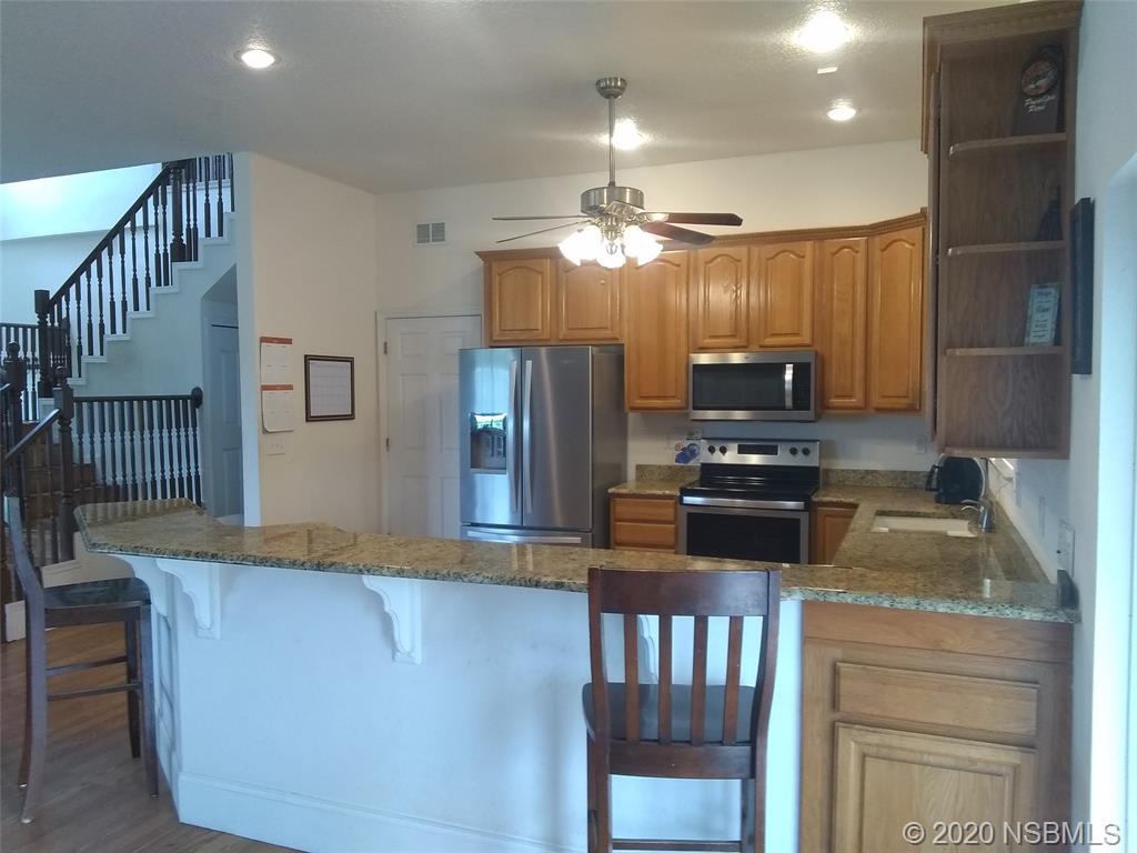 415 Stacy Grove Road Oak Hill, FL 32759 - Photo 13 of 25 a kitchen with stainless steel appliances granite countertop a refrigerator a sink dishwasher a stove and a dining table with wooden floor