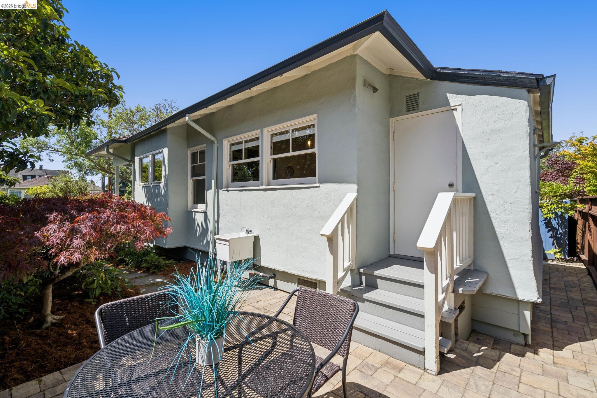 1701 Derby Street Berkeley, CA 94703 - Photo 33 of 39 Outdoor patio area featuring paver flooring, a tiered wooden staircase with handrails, and a stucco exterior