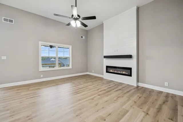 a view of an empty room with wooden floor fireplace and a window