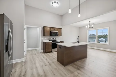 a large kitchen with a center island wooden floor stainless steel appliances and windows