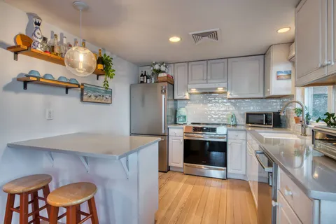 a kitchen with kitchen island stainless steel appliances a stove refrigerator sink and microwave