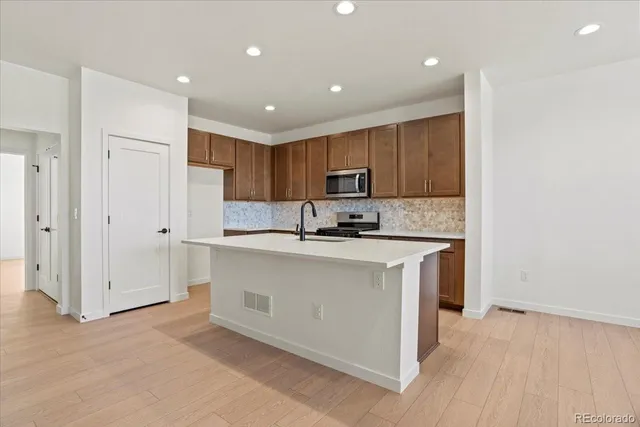 a kitchen with stainless steel appliances granite countertop a stove a sink and a refrigerator with wooden floor