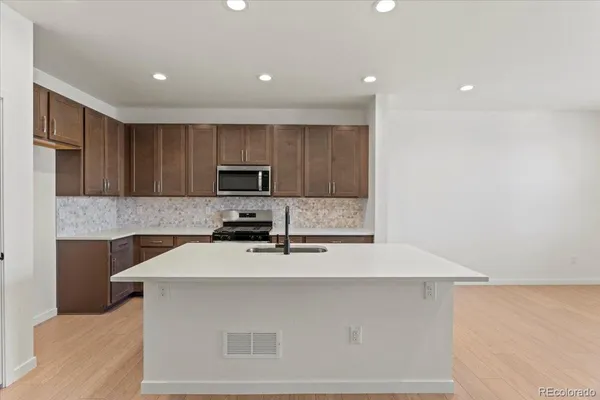 a kitchen with kitchen island a sink stainless steel appliances and cabinets