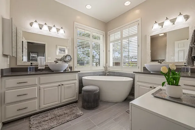 a spacious bathroom with a granite countertop sink a large mirror and a bathtub