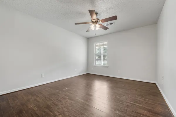 an empty room with wooden floor fan and windows