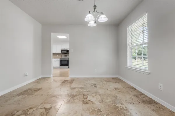 an empty room with chandelier and windows