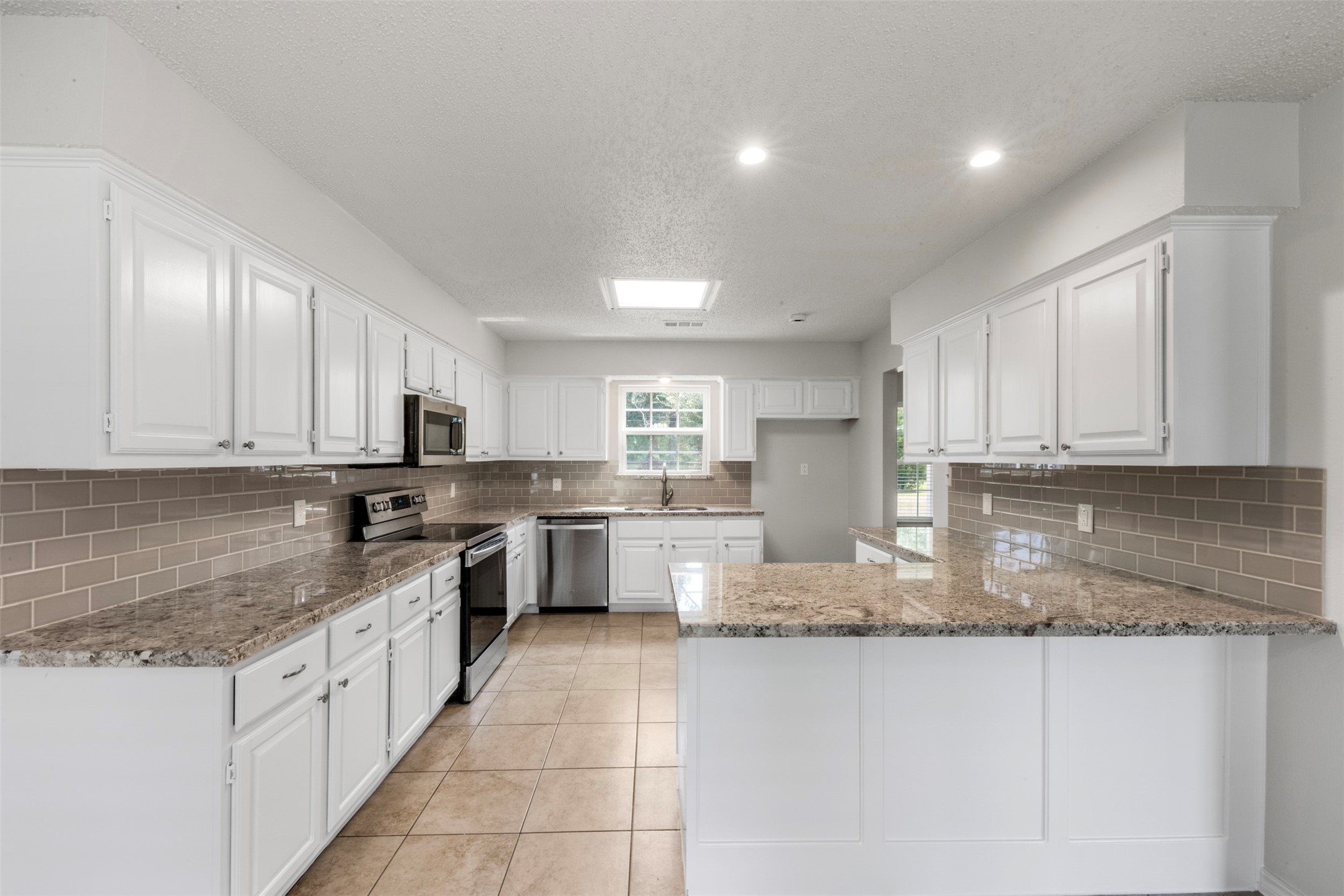 28081 Ivy Oaks Lane Splendora, TX 77372 - Photo 5 of 27 a large kitchen with granite countertop a large counter top space a sink stainless steel appliances and cabinets