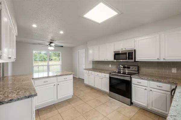 a kitchen with white cabinets appliances a sink and a window
