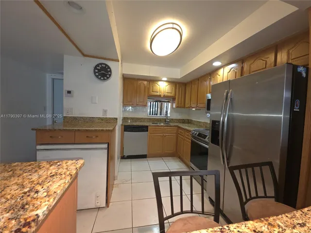 a kitchen with stainless steel appliances kitchen island granite countertop a refrigerator a stove and a sink