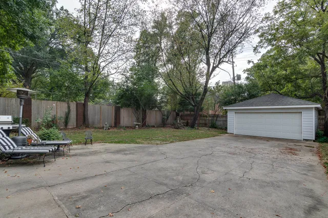 a view of backyard with wooden fence and a large tree