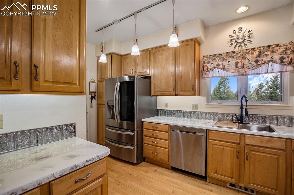 4053 Omer Lane Divide, CO 80814 - Photo 13 of 45 a kitchen with stainless steel appliances granite countertop a refrigerator a sink dishwasher and wooden cabinets with wooden floor