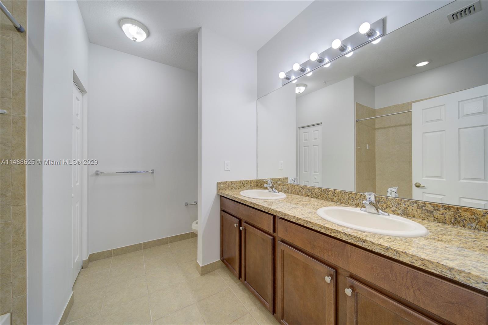 14679 Southwest 9th Street, Unit 1801 Pembroke Pines, FL 33027 - Photo 20 of 26 a bathroom with a granite countertop sink a large mirror and a shower