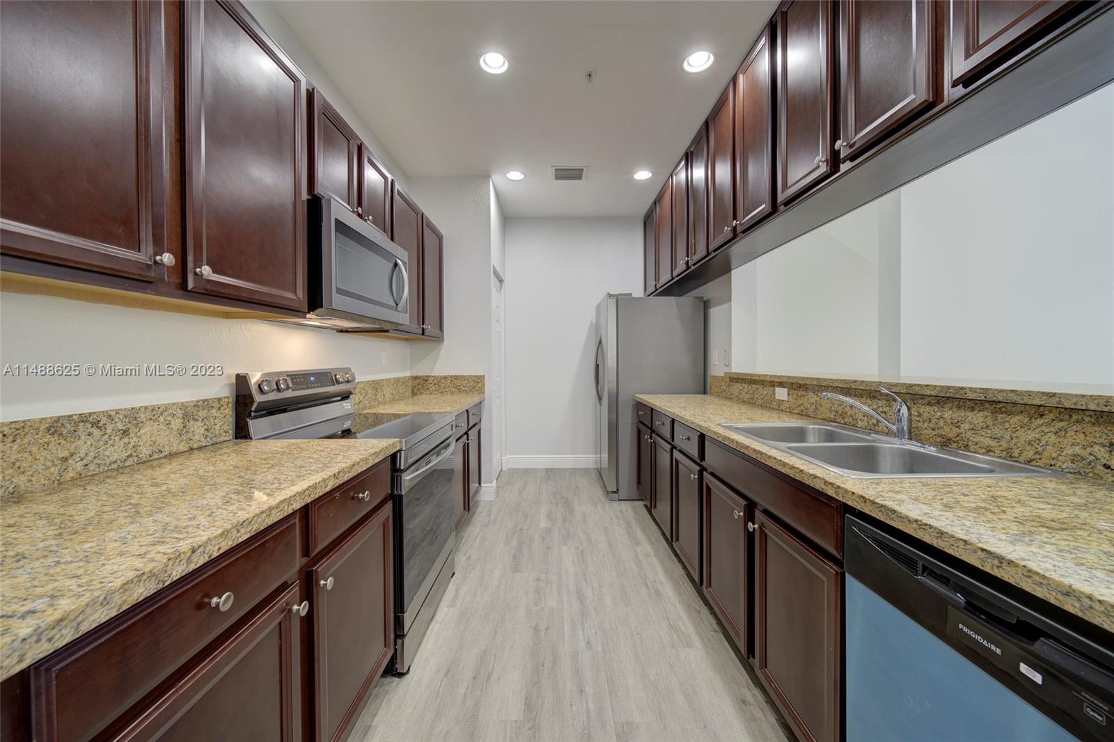 14679 Southwest 9th Street, Unit 1801 Pembroke Pines, FL 33027 - Photo 5 of 26 a large kitchen with stainless steel appliances granite countertop plenty wooden cabinets and granite counter tops