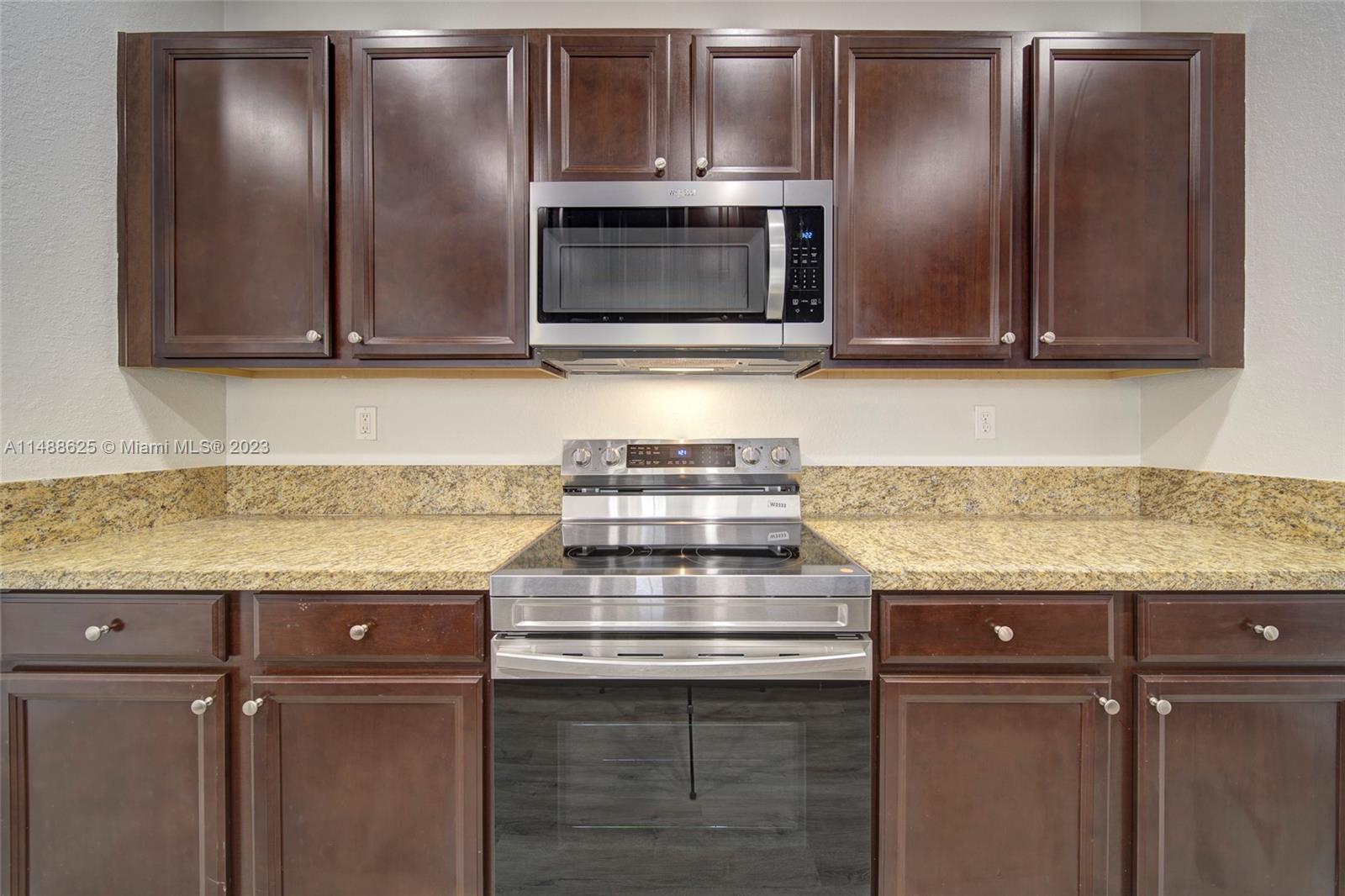 14679 Southwest 9th Street, Unit 1801 Pembroke Pines, FL 33027 - Photo 6 of 26 a kitchen with granite countertop stainless steel appliances and wooden cabinets