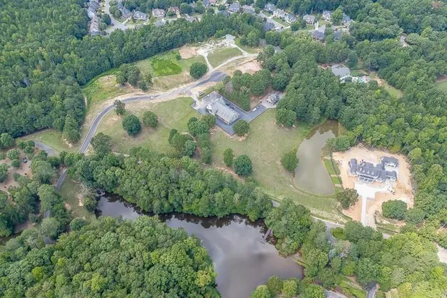 an aerial view of residential house with outdoor space and trees all around